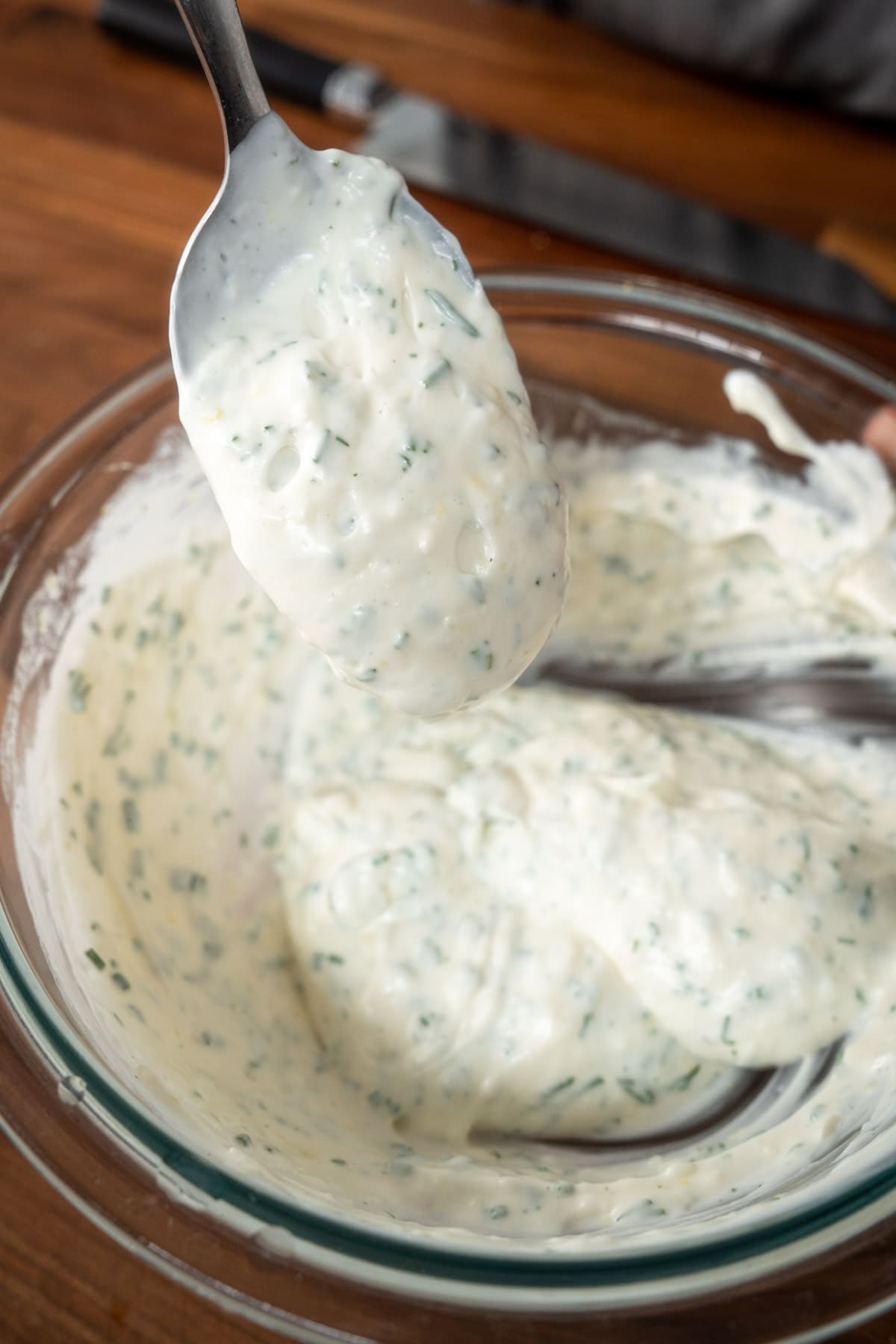mixed garlic-dill yogurt sauce on a spoon showing its thicker consistency.